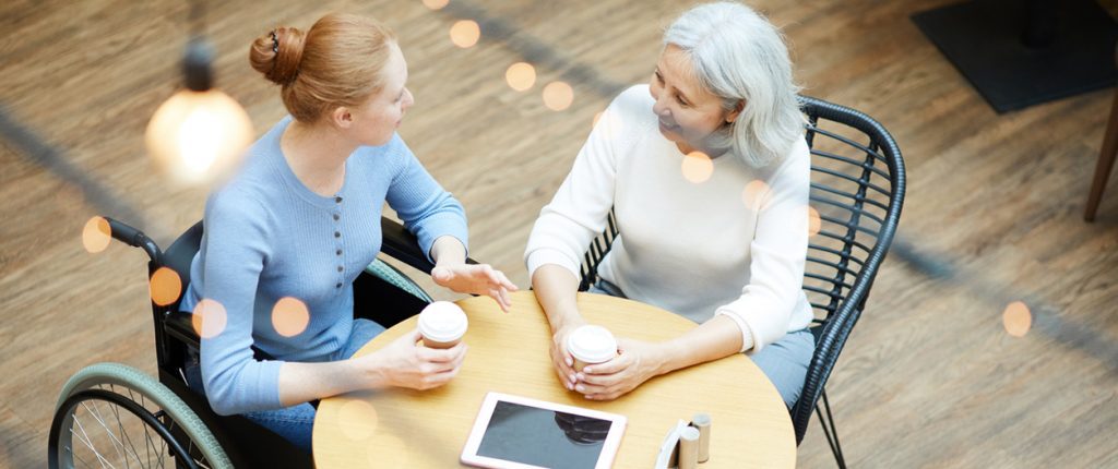 Family of two sitting at the table talking to each other and drinking coffee at cafe after shopping in shopping mall